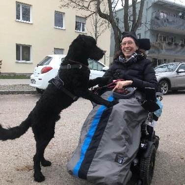 Cooper draußen mit Janina im Rollstuhl im Winterfußsack
