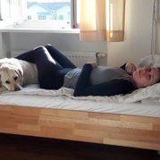 Assistenzhund Hermine stützt die Beine von Clara auf dem Bett